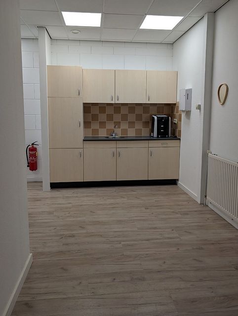 Pantry met een keukenblok van lichte kastjes, een aanrecht met spoelbak en tegelwerk, en een radiator.